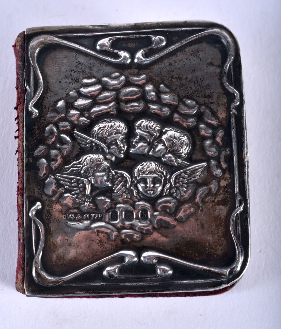An Edwardian Common Prayer Book with Silver decoration in the form of Scrolls and Cherubs. Hallmarke: An Edwardian Common Prayer Book with Silver decoration in the form of Scrolls and Cherubs. Hallmarked Birmingham 1907. 4.5cm x 5.4cm x 1.6cm, weight 30g