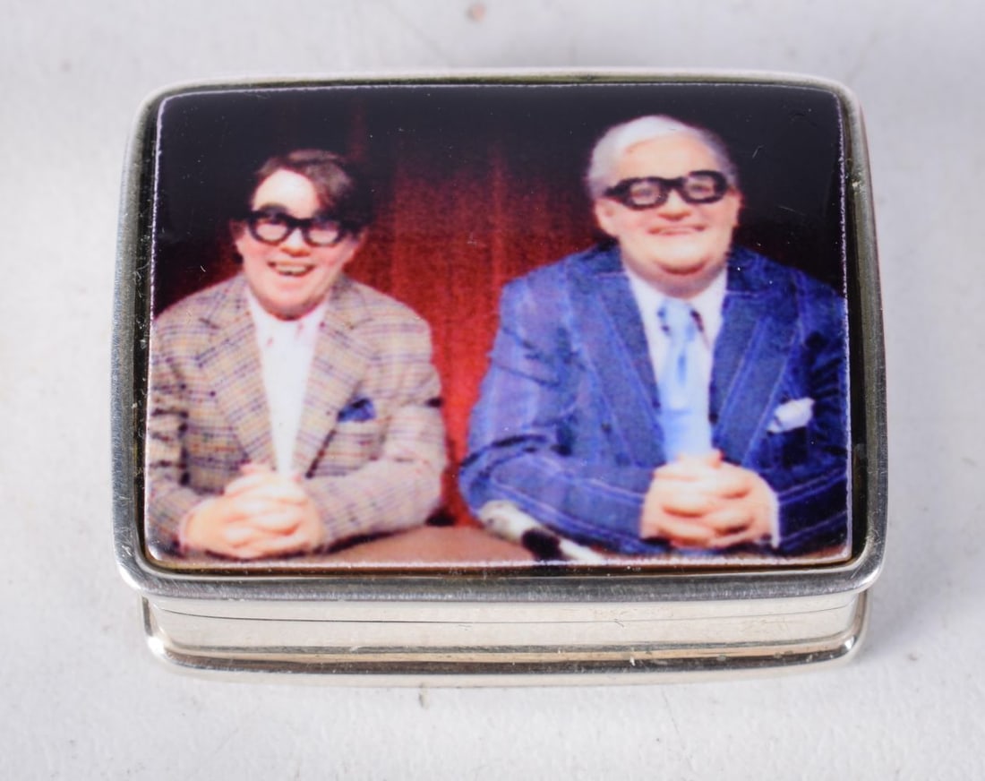 A Silver Pill Box with "The Two Ronnies" decorated Lid. Stamped 925. 1.3cm x 3.2cm x 2.5cm, weight 2: A Silver Pill Box with "The Two Ronnies" decorated Lid. Stamped 925. 1.3cm x 3.2cm x 2.5cm, weight 20g