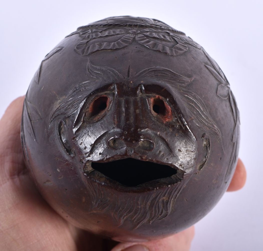 A SMALLER 18TH/19TH CENTURY CARVED COCONUT BUG BEAR FLASK decorated with a central panel of arms, fl: A SMALLER 18TH/19TH CENTURY CARVED COCONUT BUG BEAR FLASK decorated with a central panel of arms, flanked by foliage and vines. 12 cm x 8.5 cm. Note: ?Bugbear? coconut shell powder flasks, were repute