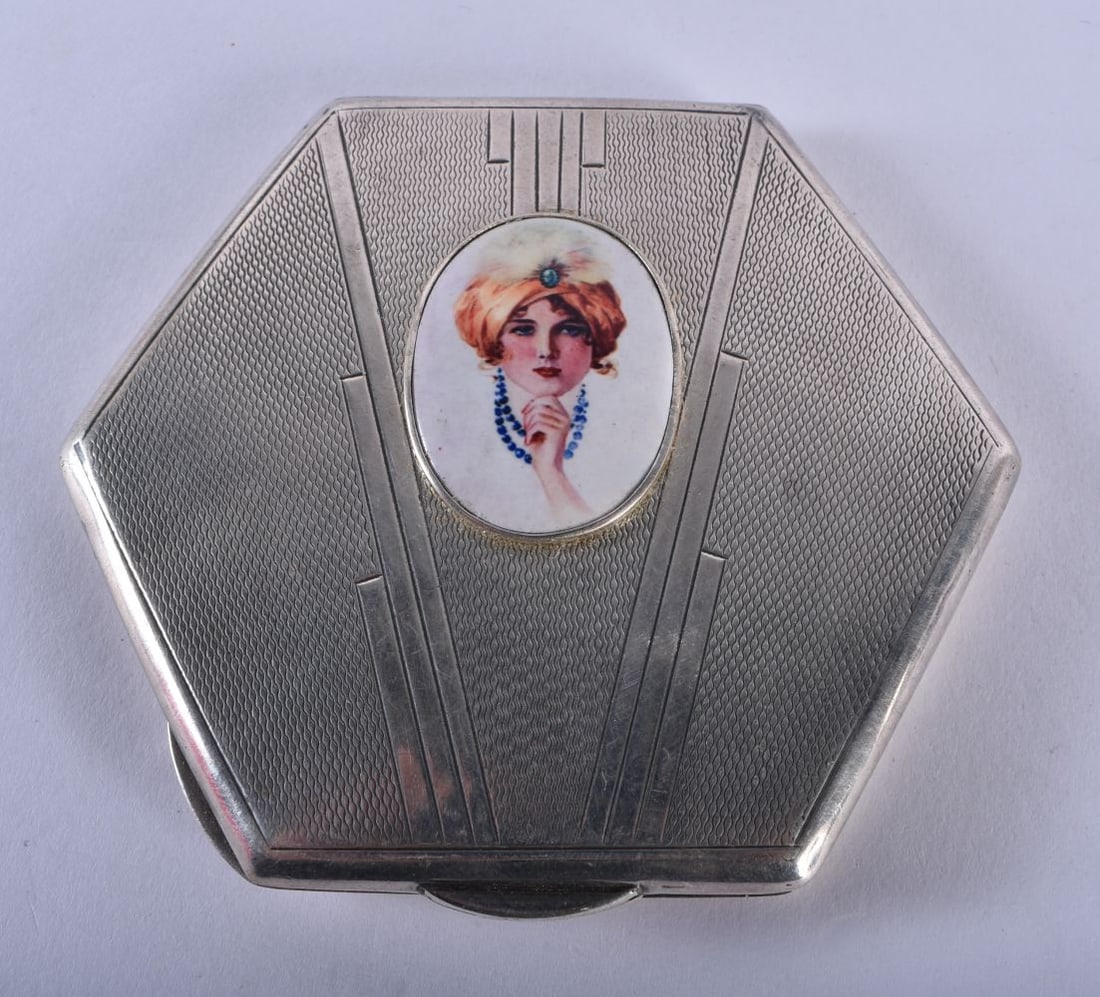 A Silver Compact with an enamel cabochon depicting an Art Deco Girl. Hallmarked Birmingham 1934. 7: A Silver Compact with an enamel cabochon depicting an Art Deco Girl. Hallmarked Birmingham 1934. 7.4cm x 8.3cm x 1.2 cm, weight 87.8g