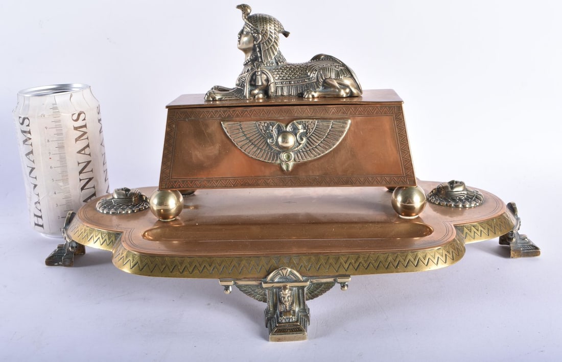 A LOVELY LARGE 19TH CENTURY ENGLISH EGYPTIAN REVIVAL DESK STAND formed with a recumbent sphinx, upon: A LOVELY LARGE 19TH CENTURY ENGLISH EGYPTIAN REVIVAL DESK STAND formed with a recumbent sphinx, upon a base decorated with mask heads. 34 cm x 18 cm.