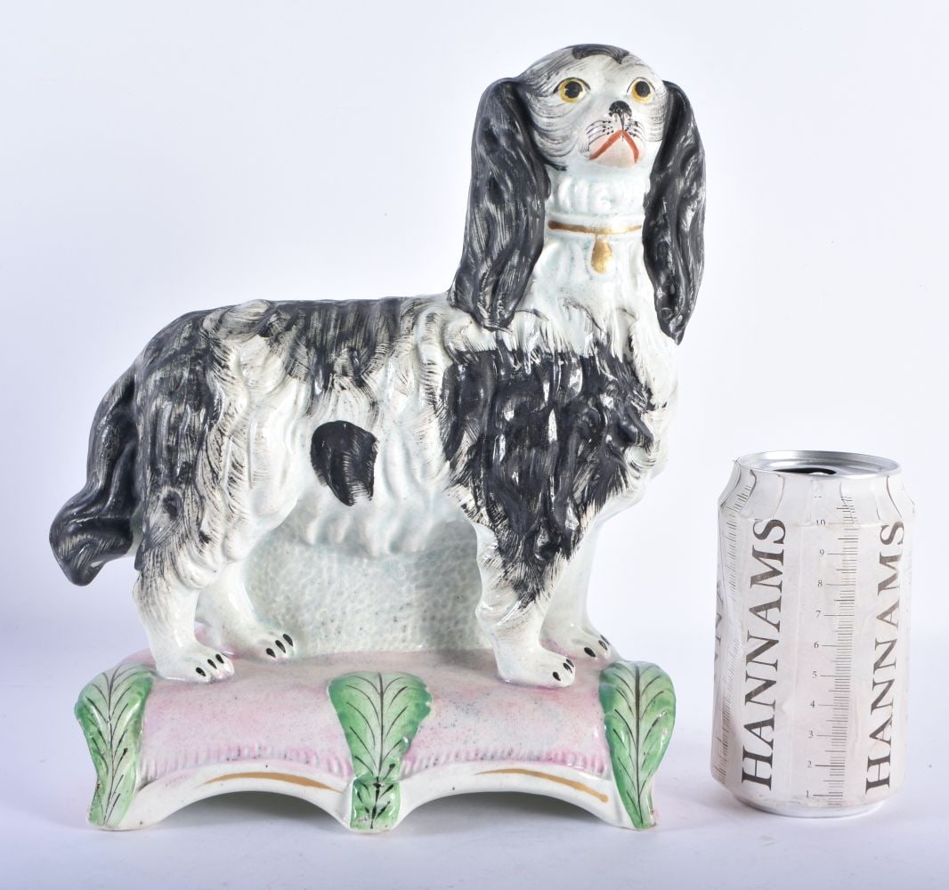A VERY RARE 19TH CENTURY STAFFORDSHIRE POTTERY BLACK AND WHITE SPANIEL modelled standing upon a pink: A VERY RARE 19TH CENTURY STAFFORDSHIRE POTTERY BLACK AND WHITE SPANIEL modelled standing upon a pink base overlaid with vines. 26 cm x 20 cm.