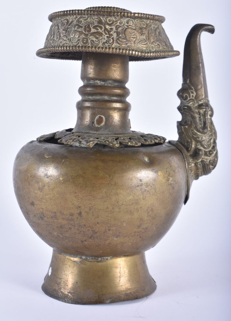 AN 18TH/19TH CENTURY TIBETAN REPOUSSE EWER formed with a mask head spout. 22cm x 13 cm.: AN 18TH/19TH CENTURY TIBETAN REPOUSSE EWER formed with a mask head spout. 22cm x 13 cm.