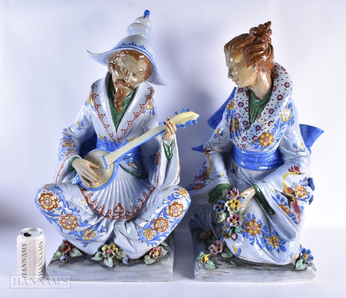A VERY LARGE PAIR OF ITALIAN CERAMIC POTTERY FIGURES OF A MALE AND FEMALE modelled in robes embellis: A VERY LARGE PAIR OF ITALIAN CERAMIC POTTERY FIGURES OF A MALE AND FEMALE modelled in robes embellished with flowers. 62 cm x 32 cm.