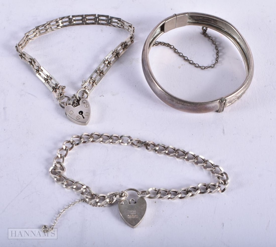 A Silver Cuff Bangle together with Two Link Bracelets with Heart Locks. Various Hallmarks incl Lond: A Silver Cuff Bangle together with Two Link Bracelets with Heart Locks. Various Hallmarks incl London 1979. Longest Bracelet 19cm, total weight 30.1g (3)