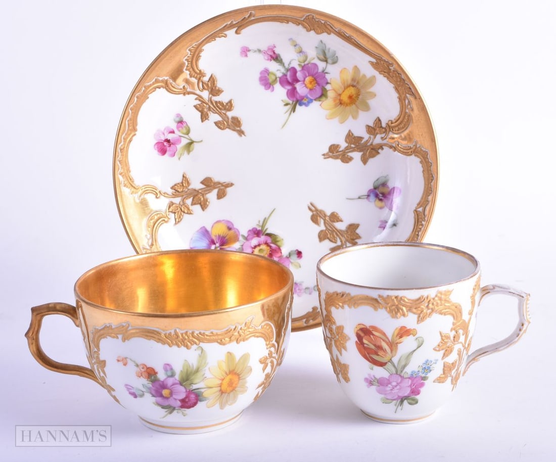 Berlin teacup coffee cup and saucer painted with flowers in raised gilt panels, blue sceptre mark an: Berlin teacup coffee cup and saucer painted with flowers in raised gilt panels, blue sceptre mark and KPM and orb in red. 12 cm diameter. (3)