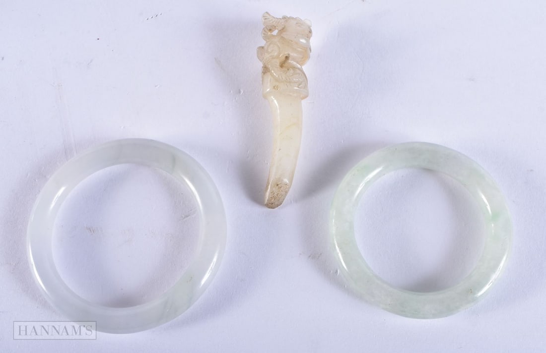 TWO CHINESE QING DYNASTY JADE BANGLES together with a jade hair pin. Largest 6.5 cm long. (3): TWO CHINESE QING DYNASTY JADE BANGLES together with a jade hair pin. Largest 6.5 cm long. (3)