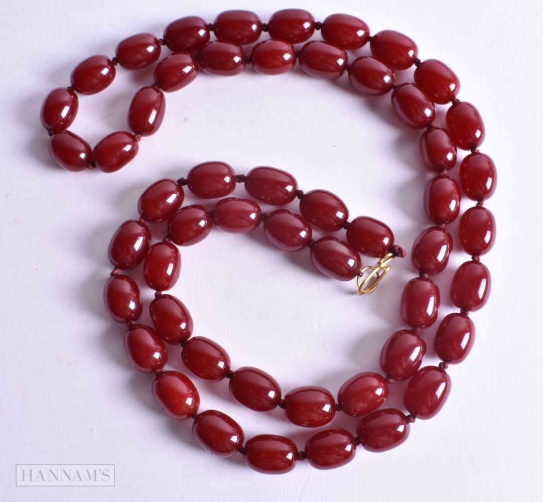 A CHERRY BEAD NECKLACE possibly amber. 145 grams. 105 cm long, each bead 1.5 cm x 1 cm.: A CHERRY BEAD NECKLACE possibly amber. 145 grams. 105 cm long, each bead 1.5 cm x 1 cm.