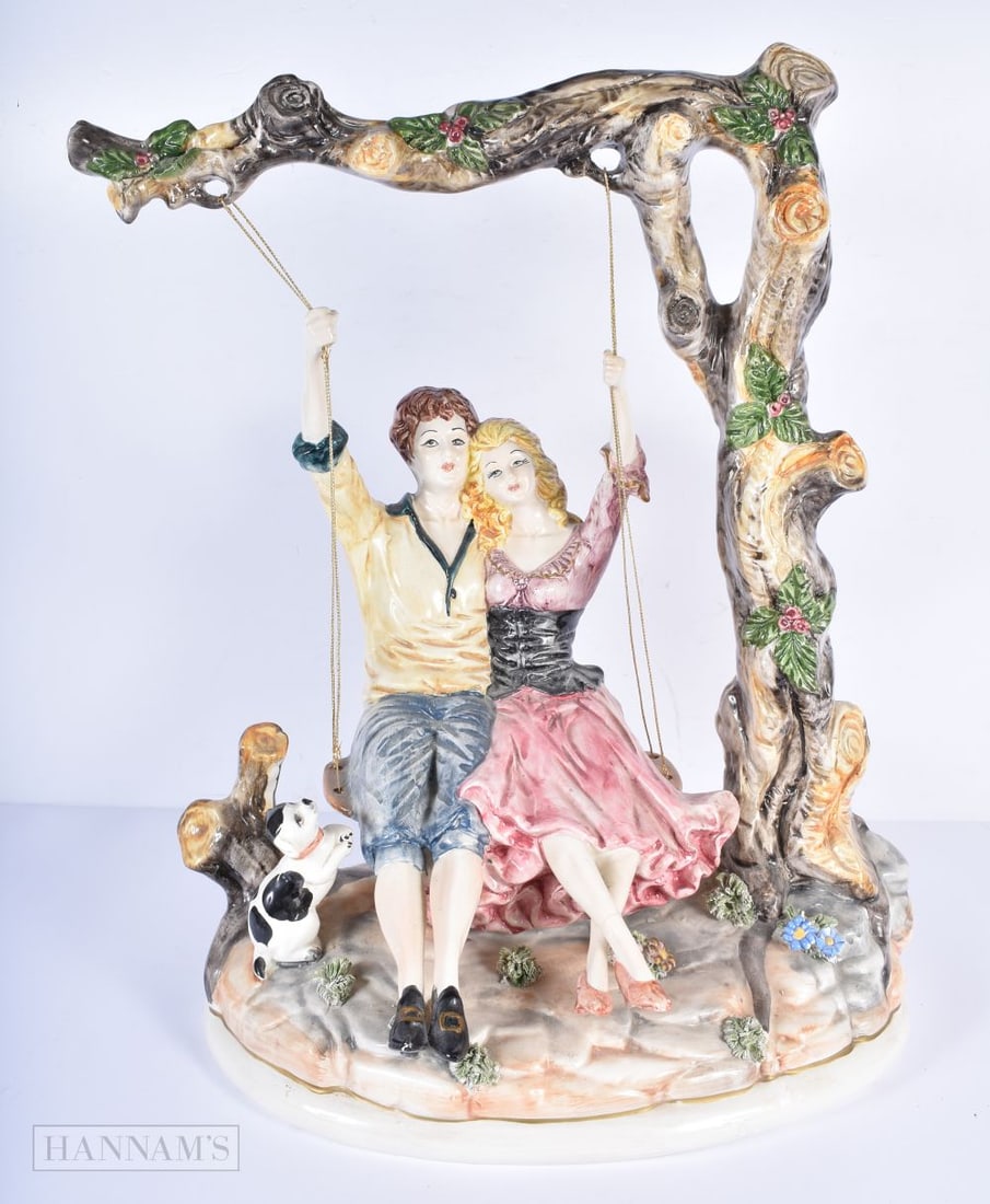 A large Capodimonte figure depicting a couple on a tree swing 53 x 40 x 27cm: A large Capodimonte figure depicting a couple on a tree swing 53 x 40 x 27cm