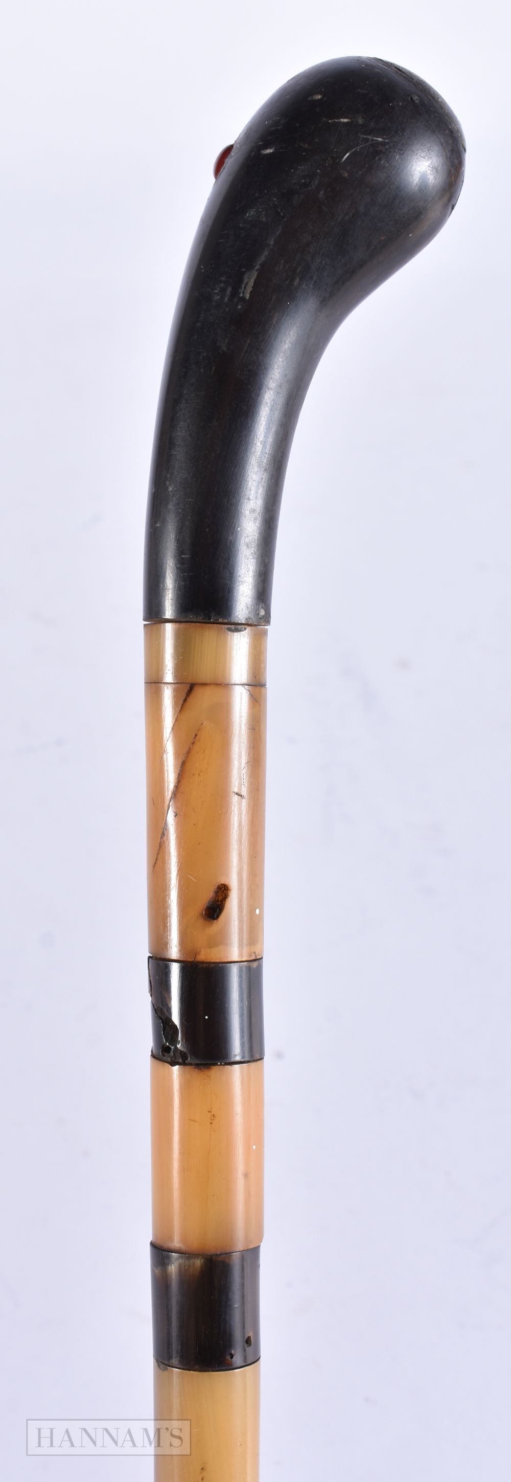 A 19TH CENTURY MIDDLE EASTERN CARVED RHINOCEROS HORN TOPPED WALKING CANE with sectional horn shaft.: A 19TH CENTURY MIDDLE EASTERN CARVED RHINOCEROS HORN TOPPED WALKING CANE with sectional horn shaft. 88 cm long.