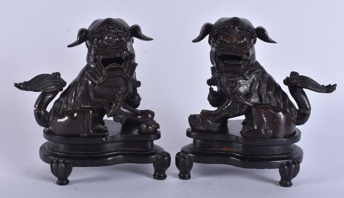 A PAIR OF 18TH CENTURY CHINESE BRONZE FIGURES OF BUDDHIST LIONS modelled upon fitted hardwood bases.