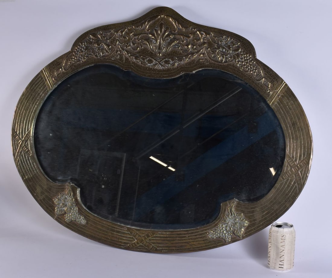 A LARGE ARTS AND CRAFTS BRASS MIRROR overlaid with berries and vines. 86 cm x 68 cm. (1 of 4)