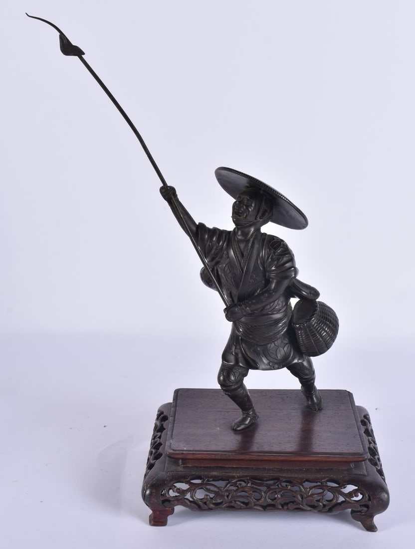 A 19TH CENTURY JAPANESE MEIJI PERIOD BRONZE OKIMONO modelled as a male with a speared bird. Bronze 2 (1 of 8)