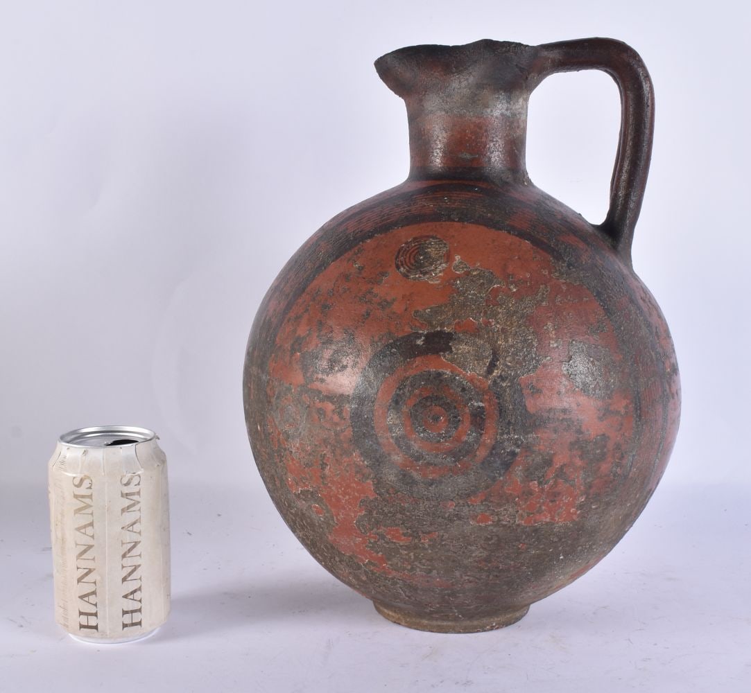 A LARGE ANCIENT CYPRIOT BLACK ON RED POTTERY OENOCHOE the spherical body decorated with multiple con: A LARGE ANCIENT CYPRIOT BLACK ON RED POTTERY OENOCHOE the spherical body decorated with multiple concentric circles, vertical crossed lines to the front, conjoined handle and trefoil lip, iron age, C7