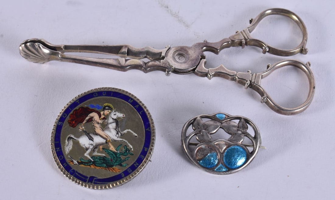 A CHARLES HORNER SILVER AND ENAMEL BROOCH together with an enamelled coin & a pair of silver tongs. (1 of 3)