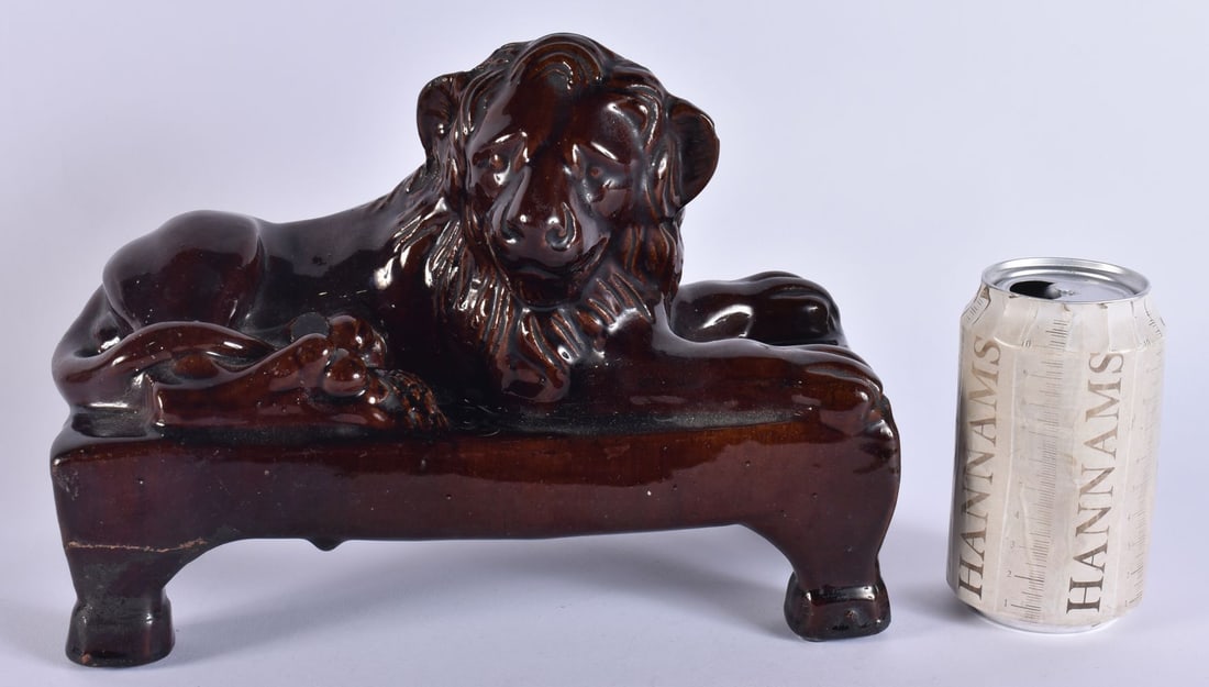 AN EARLY 19TH CENTURY ENGLISH TREACLE GLAZED FIGURE OF A LION modelled upon a rectangular plinth. 27 (1 of 6)