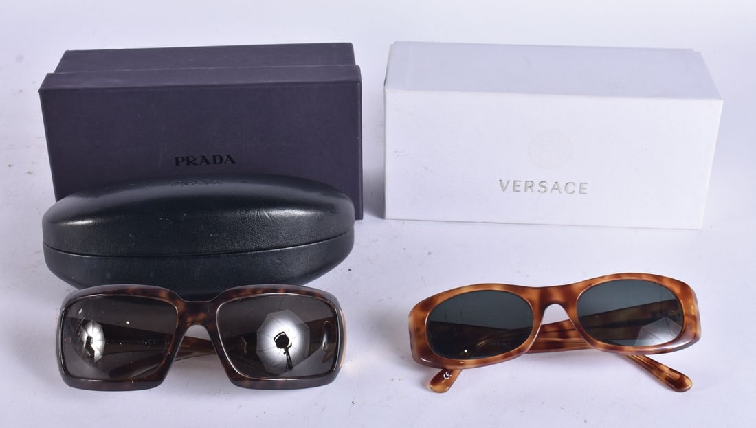 Designer Sunglasses Prada & Gianni Versace Inc Boxes & Case. (2) WE ARE UNABLE TO SHIP THIS LOT TO: Designer Sunglasses Prada & Gianni Versace Inc Boxes & Case. (2) WE ARE UNABLE TO SHIP THIS LOT TO USA/CANADA