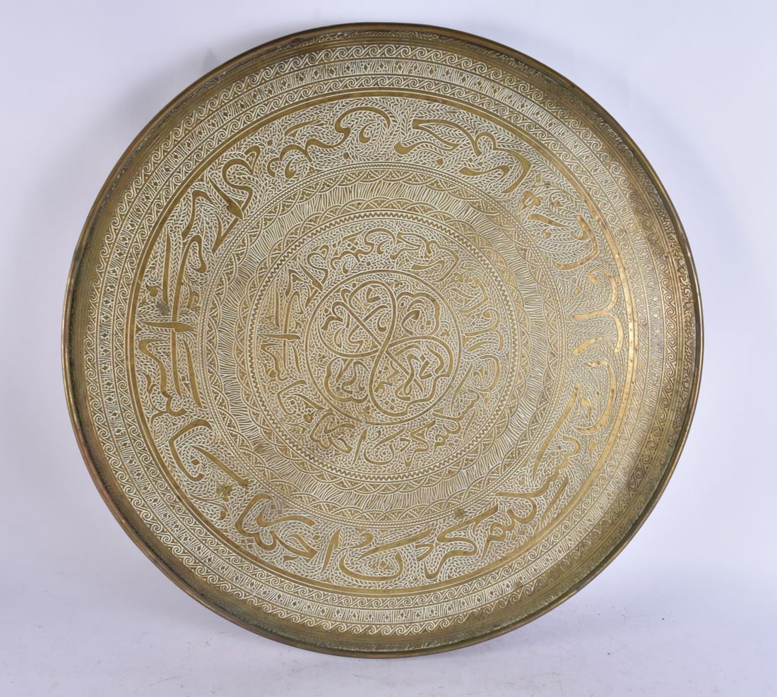 AN ISLAMIC BRASS CIRCULAR TABLE upon a wooden base. 44 cm wide, 60 cm high. (1 of 5)