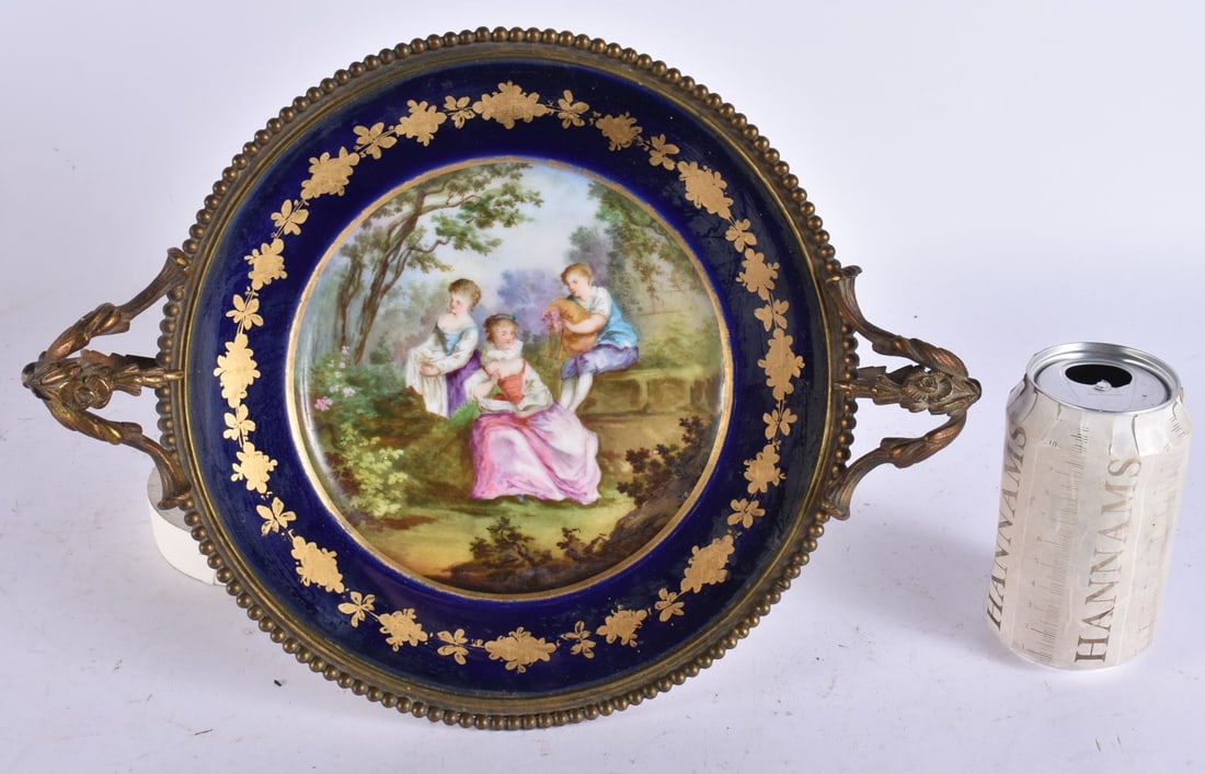 A 19TH CENTURY FRENCH SEVRES PORCELAIN AND GILT BRONZE COMPORT painted with figures in a landscape.: A 19TH CENTURY FRENCH SEVRES PORCELAIN AND GILT BRONZE COMPORT painted with figures in a landscape. 32 cm wide.