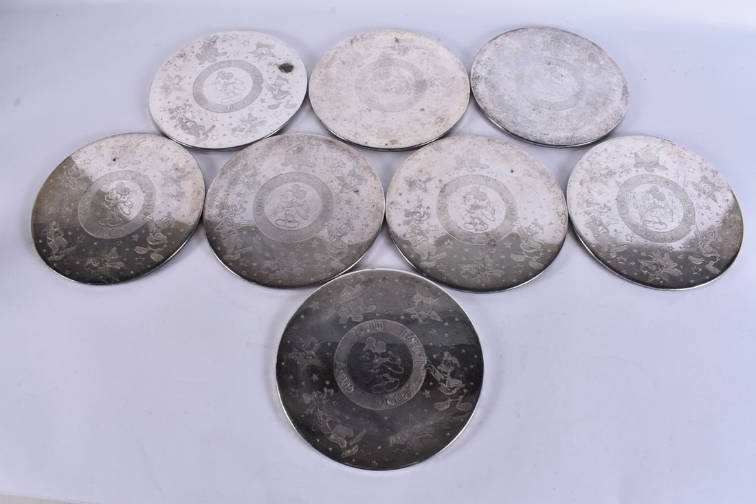 A set of eight Walt Disney Productions silver plated coasters engraved with Disney figures, 19 cm di: A set of eight Walt Disney Productions silver plated coasters engraved with Disney figures, 19 cm diameter. (8)