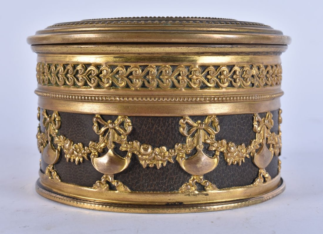 A LATE 19TH CENTURY FRENCH GILT METAL AND LEATHER CIRCULAR BOX AND COVER decorated with foliage and (1 of 4)