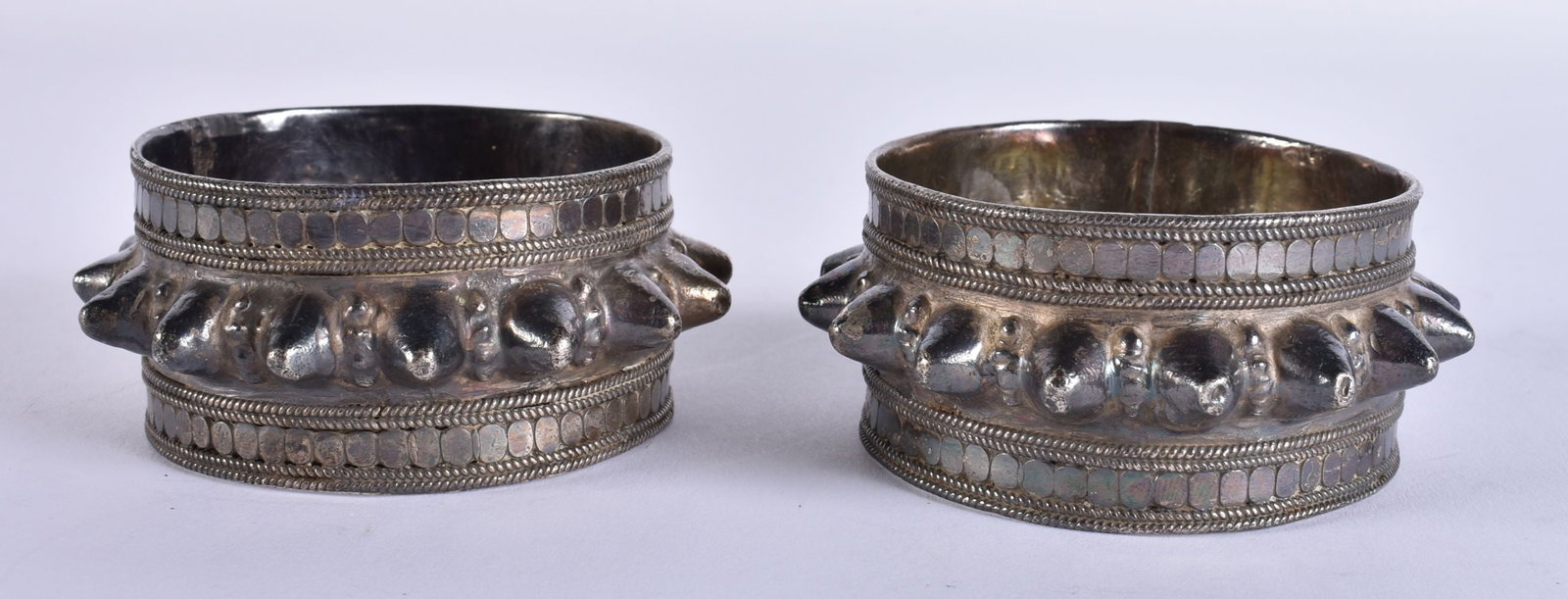 A PAIR OF ANTIQUE MIDDLE EASTERN SILVER BANGLES. 174 grams. 7 cm wide. (1 of 3)