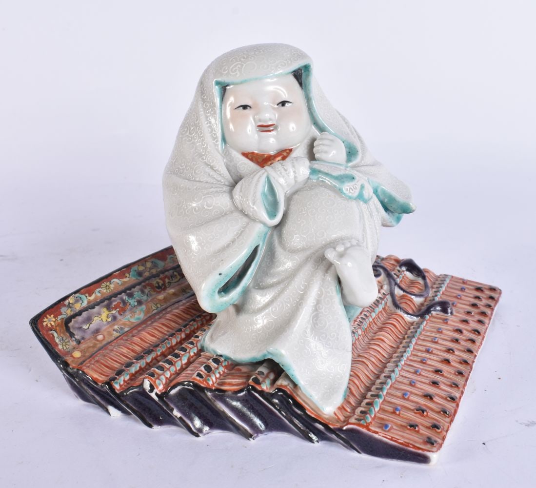A 19TH CENTURY JAPANESE MEIJI PERIOD PORCELAIN FIGURE modelled as a child upon a fabric. 15 cm x 15 (1 of 5)