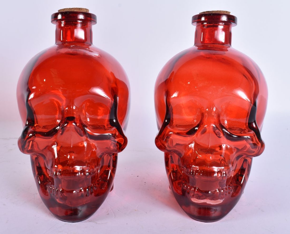 A PAIR OF RUBY GLASS SKULL BOTTLES. 18 cm high. (1 of 4)