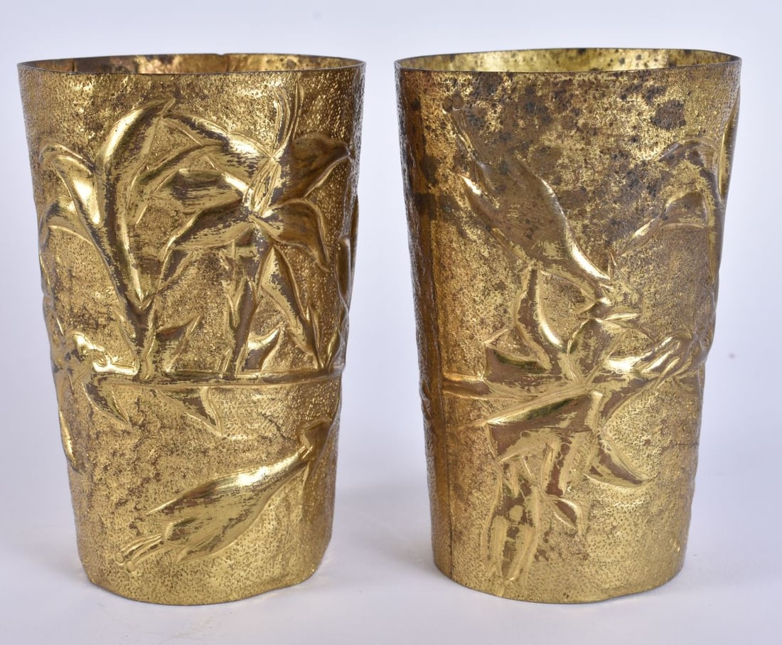 A PAIR OF ANTIQUE GILDED REPOUSSE BEAKERS decorated with foliage. 11 cm x 7.5 cm. (1 of 5)