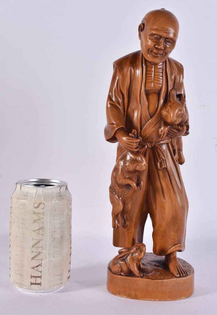 A LATE 19TH CENTURY JAPANESE MEIJI PERIOD CARVED BOXWOOD OKIMONO modelled as a male holding hares. 3 (1 of 3)
