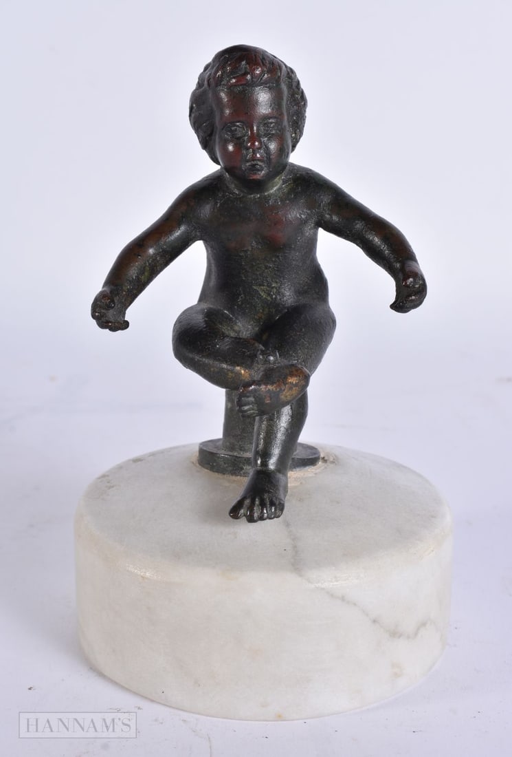 A 17TH/18TH CENTURY EUROPEAN BRONZE FIGURE OF A PUTTI modelled upon a marble base. 15 cm high. (1 of 12)
