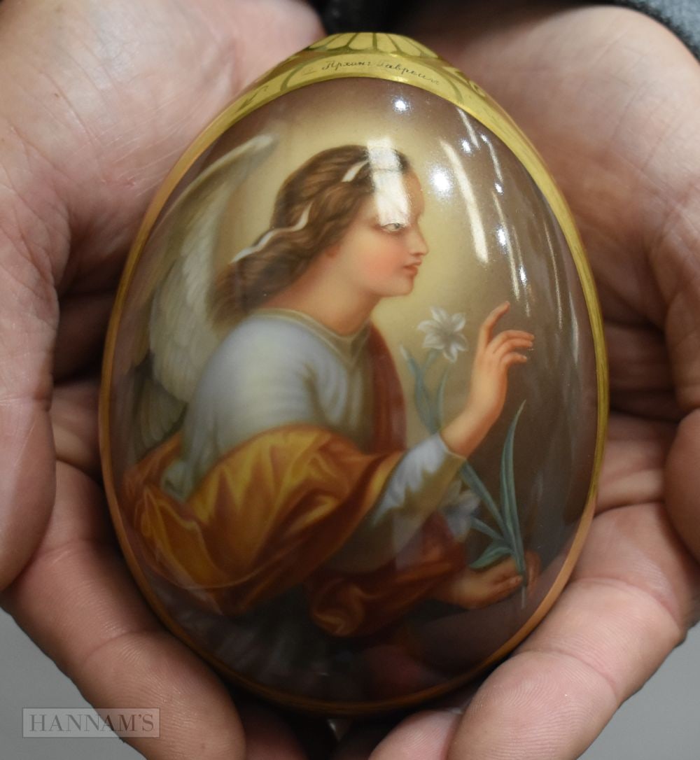 A FINE LARGE RUSSIAN PORCELAIN PAINTED EASTER EGG decorated with a saint holding a flower, initialle (1 of 5)