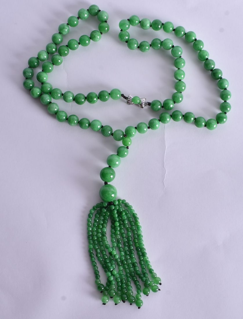 A green Jade Bead Necklace with a Tassel Pendant and 14 Carat White Gold Clasp. Stamped 14K 585. Le: A green Jade Bead Necklace with a Tassel Pendant and 14 Carat White Gold Clasp. Stamped 14K 585. Length 84cm, weight 145.8g