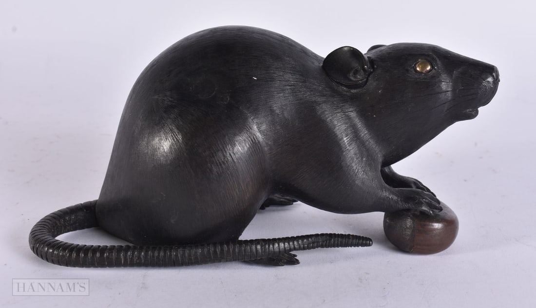 A 19TH CENTURY JAPANESE MEIJI PERIOD BRONZE RAT OKIMONO modelled clutching a nut. 15 cm wide.: A 19TH CENTURY JAPANESE MEIJI PERIOD BRONZE RAT OKIMONO modelled clutching a nut. 15 cm wide.
