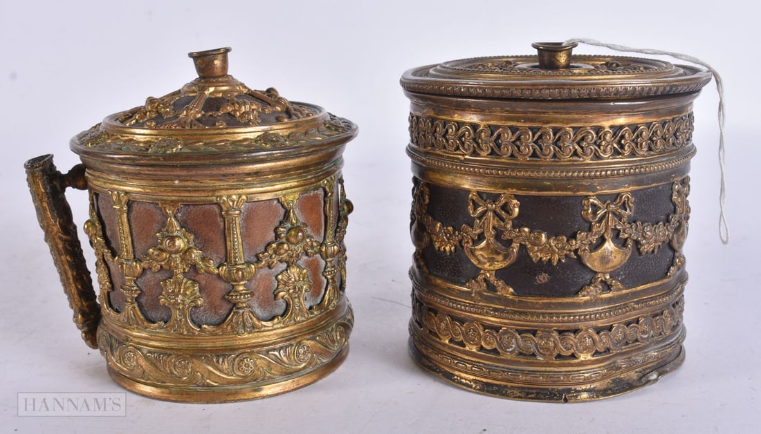 A 19TH CENTURY FRENCH GILT METAL LEATHER STRING BOX AND COVER together with another similar vessel,: A 19TH CENTURY FRENCH GILT METAL LEATHER STRING BOX AND COVER together with another similar vessel, overlaid with motifs. Largest 8.5 cm x 8.5 cm. (2)