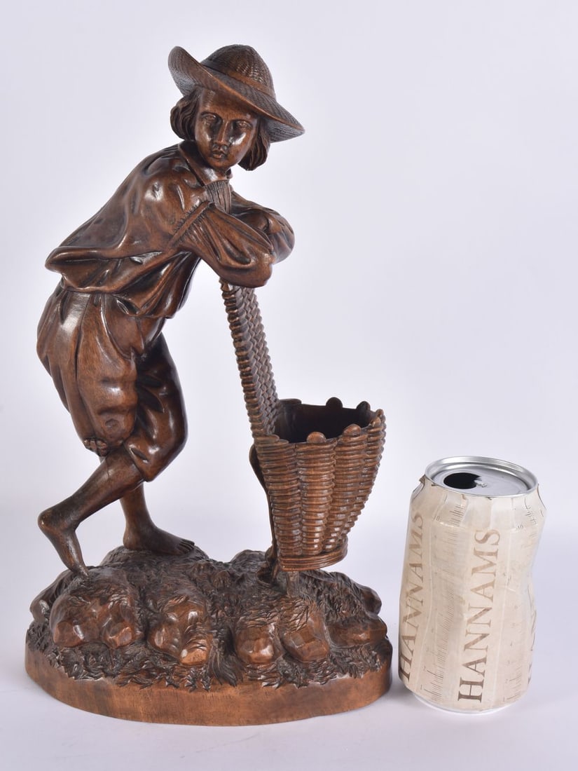 A LARGE LATE 19TH CENTURY BAVARIAN BLACK FOREST FIGURE OF A BOY modelled leaning upon an open basket: A LARGE LATE 19TH CENTURY BAVARIAN BLACK FOREST FIGURE OF A BOY modelled leaning upon an open basket. 32 cm x 14 cm.