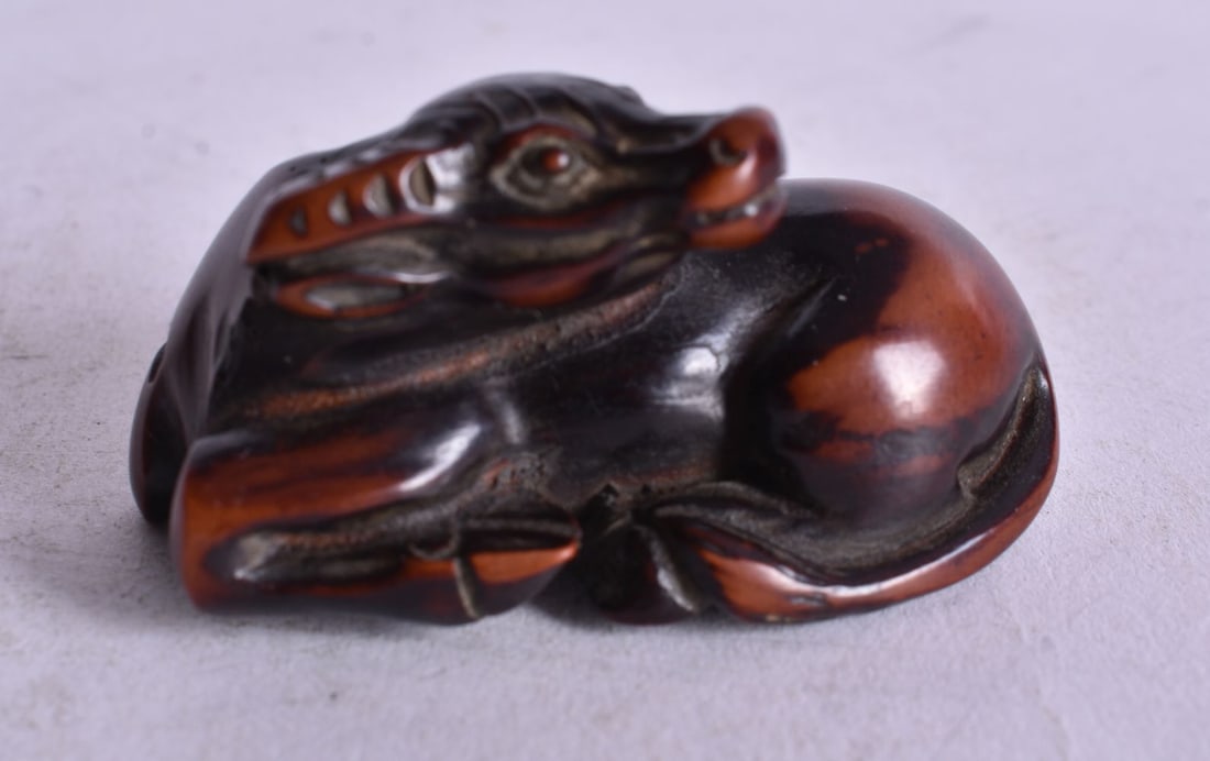 A 19TH CENTURY JAPANESE MEIJI PERIOD CARVED WOOD NETSUKE modelled as a bull. 5 cm x 2.25cm. (1 of 3)