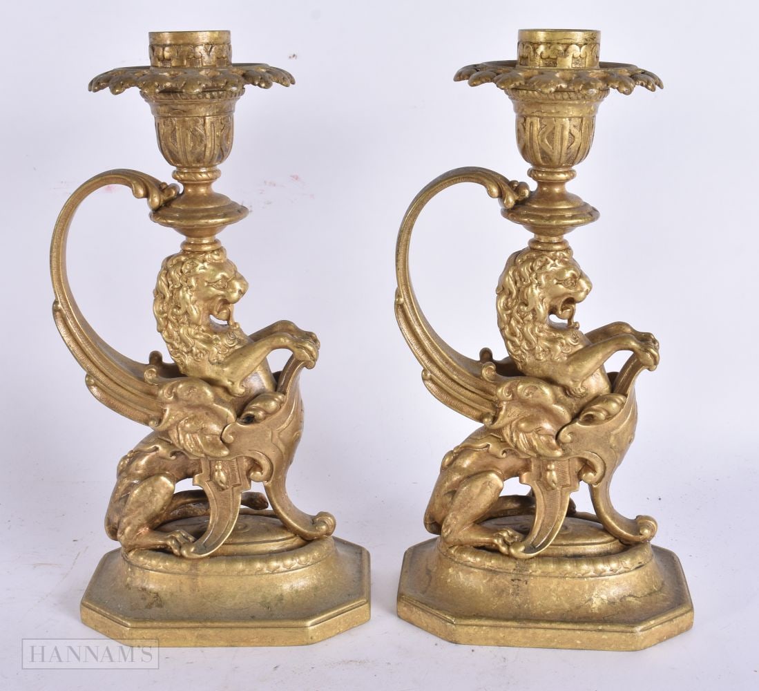 A PAIR OF 19TH CENTURY BRONZE CANDLESTICKS stamped CHL, formed as rampant lions holding shields. 23.: A PAIR OF 19TH CENTURY BRONZE CANDLESTICKS stamped CHL, formed as rampant lions holding shields. 23.5 cm high.