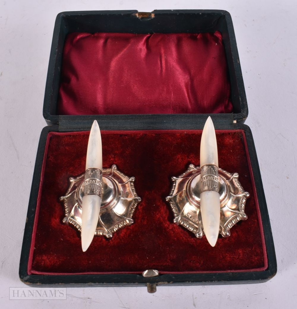 A CASED PAIR OF ANTIQUE SILVER AND MOTHER OF PEARL KNIFE RESTS. 54 grams. 7 cm wide. (1 of 4)