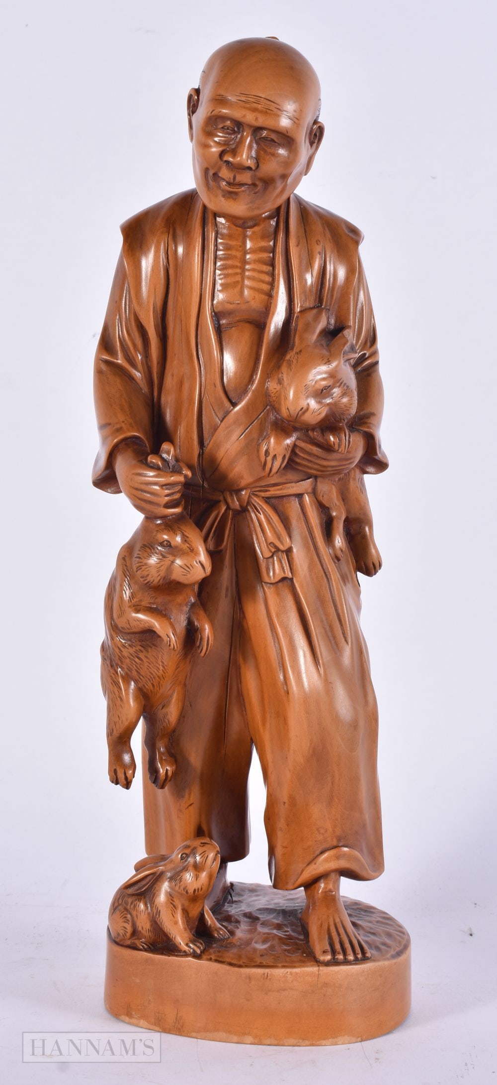 AN EARLY 20TH CENTURY JAPANESE MEIJI PERIOD CARVED WOOD OKIMONO modelled as a male carrying hares. 3: AN EARLY 20TH CENTURY JAPANESE MEIJI PERIOD CARVED WOOD OKIMONO modelled as a male carrying hares. 30 cm high.