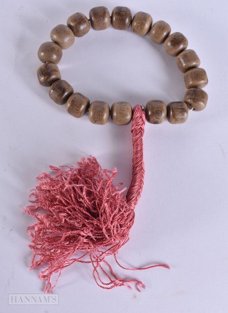 A CHINESE CARVED WOOD BRACELET possibly Agarwood. 50 cm long inc tassel. (1 of 4)