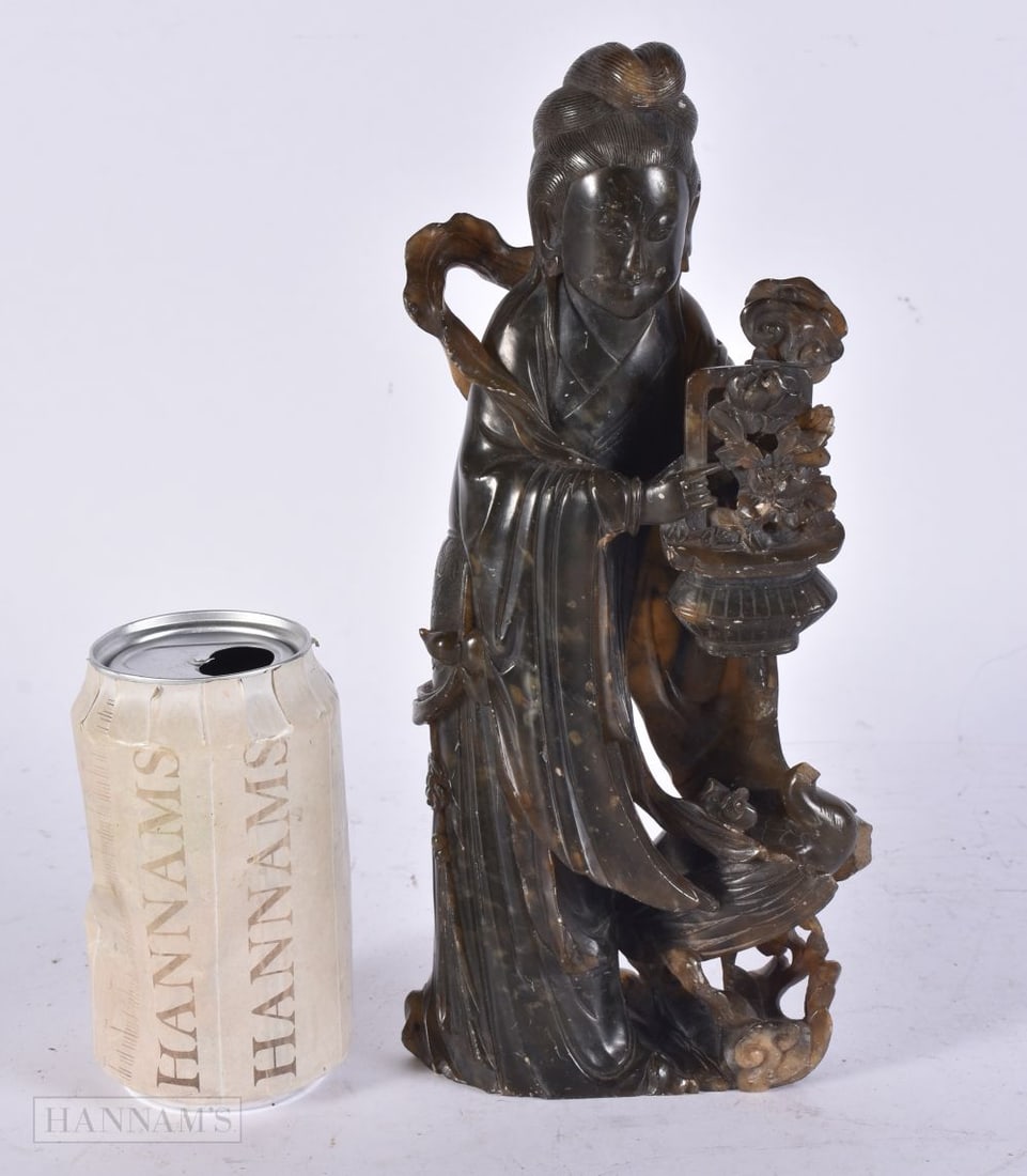 A CHINESE QING DYNASTY CARVED SOAPSTONE IMMORTAL modelled holding a basket of flowers. 26 cm high.: A CHINESE QING DYNASTY CARVED SOAPSTONE IMMORTAL modelled holding a basket of flowers. 26 cm high.