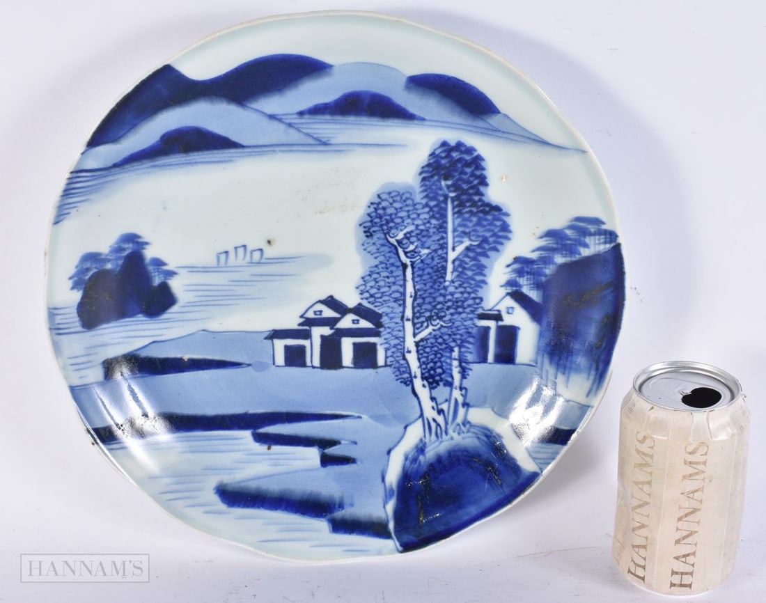A LARGE 18TH CENTURY JAPANESE EDO PERIOD BLUE AND WHITE PORCELAIN DISH painted with huts in a landsc: A LARGE 18TH CENTURY JAPANESE EDO PERIOD BLUE AND WHITE PORCELAIN DISH painted with huts in a landscape. 30 cm wide.