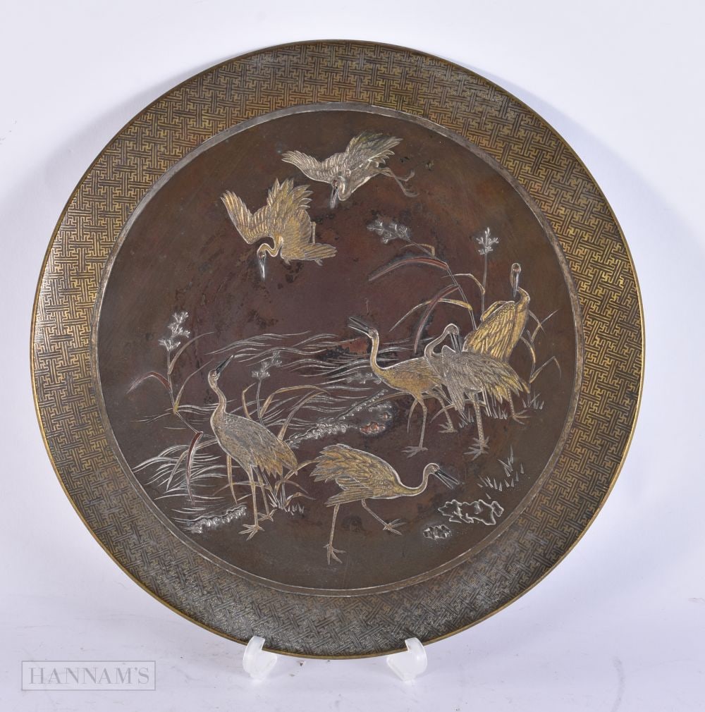 A 19TH CENTURY JAPANESE MEIJI PERIOD BRONZE PLATE decorated with birds within a river. 27 cm wide.: A 19TH CENTURY JAPANESE MEIJI PERIOD BRONZE PLATE decorated with birds within a river. 27 cm wide.