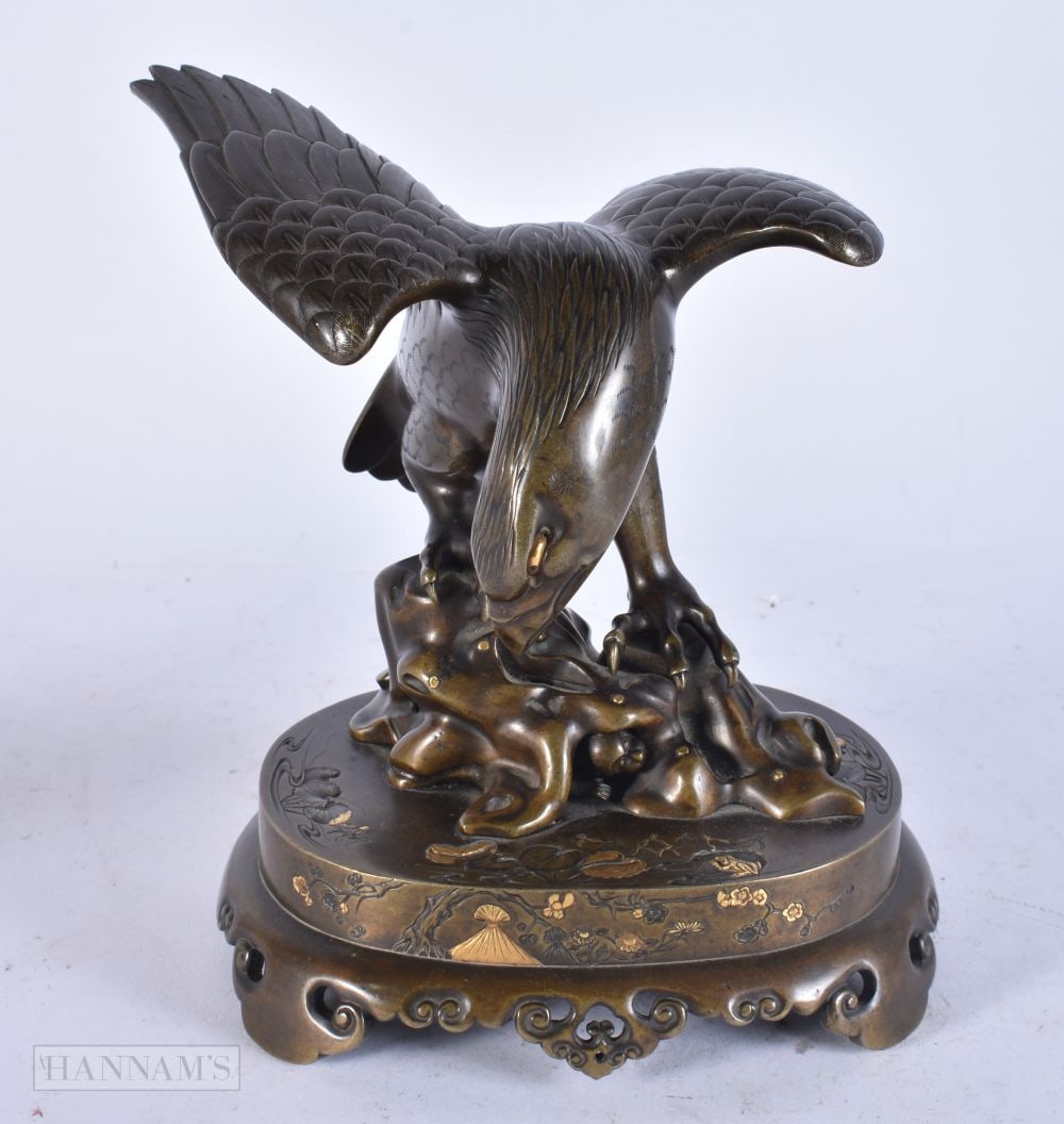 A 19TH CENTURY JAPANESE MEIJI PERIOD GOLD INLAID BRONZE HAWK OKIMONO modelled upon a base embellishe: A 19TH CENTURY JAPANESE MEIJI PERIOD GOLD INLAID BRONZE HAWK OKIMONO modelled upon a base embellished in foliage. 20 cm x 13 cm.