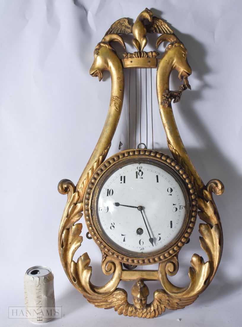 A LOVELY 19TH CENTURY EUROPEAN GILTWOOD MYRE CLOCK formed with a bird above two stylised rams heads, (1 of 2)