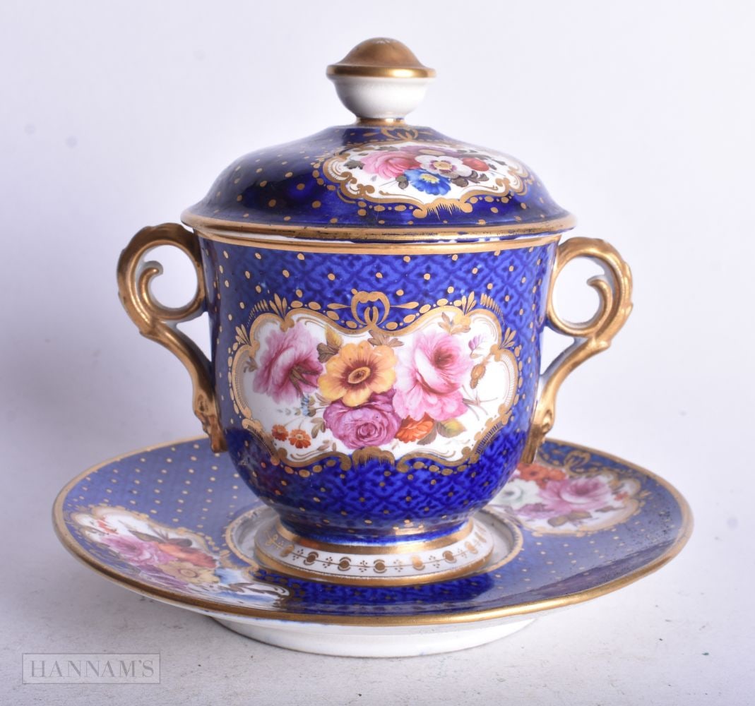 Coalport style chocolate cup, cover and saucer painted with six panels of flowers on a blue square a: Coalport style chocolate cup, cover and saucer painted with six panels of flowers on a blue square and dot ground, 12 cm high (3)