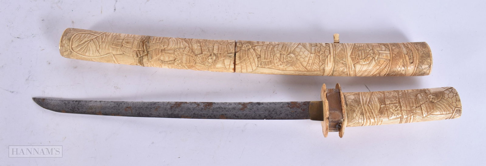 A 19TH CENTURY JAPANESE MEIJI PERIOD CARVED BONE SWORD decorated with samurai. 58 cm long.: A 19TH CENTURY JAPANESE MEIJI PERIOD CARVED BONE SWORD decorated with samurai. 58 cm long.