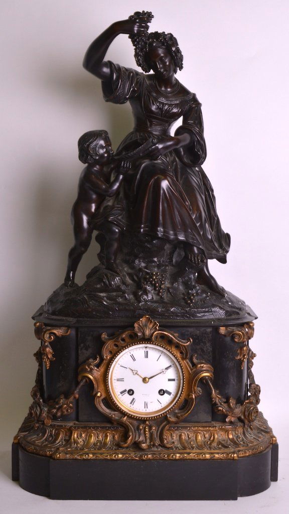 A MID 19TH CENTURY FRENCH BRONZE AND MARBLE MANTEL: A MID 19TH CENTURY FRENCH BRONZE AND MARBLE MANTEL CLOCK modelled as a seated female and young child holding aloft grapes, upon a shaped base with gilt bronze acanthus mounts. 2ft 2.5ins high. £800-1