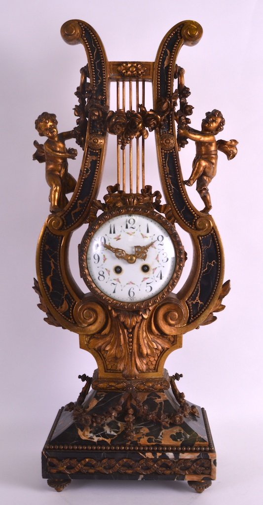 A LARGE 19TH CENTURY FRENCH ORMOLU AND VEINED MARBLE: A LARGE 19TH CENTURY FRENCH ORMOLU AND VEINED MARBLE LYRE CLOCK surmounted with putti holding flowers, the dial painted with floral sprays. 2ft 1ins high. £600-800